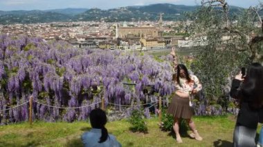 Floransa, Nisan 2023: Turistler arka planda Santa Croce Bazilikası ve Bel Purple Wisteria 'nın önündeki Bardini Bahçesi' nde selfie ve fotoğraf çekiyorlar. Floransa, İtalya.