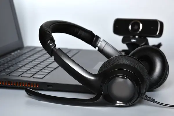 stock image Notebook with headphones with mic and a webcam, concept of smart working or online communications.