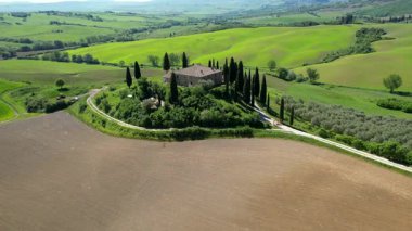 İlkbaharda Toskana 'daki bir çiftlik evinin etrafındaki Val d' Orcia tepelerinin hava manzarası. San Quirico, İtalya.