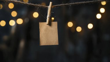 Arkaplanda parlayan bokeh ışıkları olan bir ipe asılı tek bir tahta etiket..