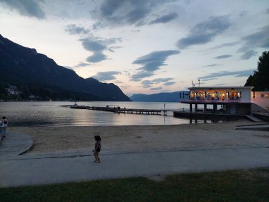 Fransa, Savoy 'daki Lac du bourget' ta alacakaranlık. Soğuk bir atmosferde açık bir restoran var. Ön planda bir çocuk