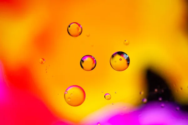 Karışık su ve yağın turuncu ve mor renkteki güzel soyut arkaplanı. Soyut makro arkaplan. Masaüstü duvar kağıdı. Doku. Renkli kabarcıklar