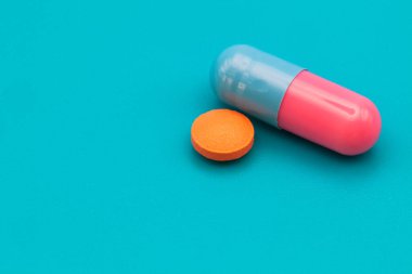 Tıbbi ilaçlar ve kapsüller masada. Mavi zemin üzerinde haplar ve metin için boşluk