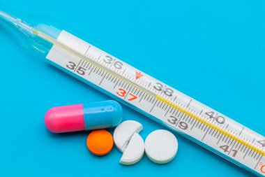 Tıbbi ilaçlar ve kapsüller masada. Mavi zemin üzerinde haplar ve metin için boşluk