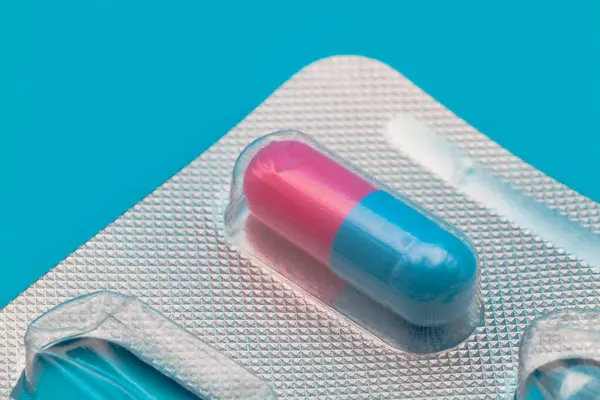 Tıbbi ilaçlar ve kapsüller masada. Mavi zemin üzerinde haplar ve metin için boşluk