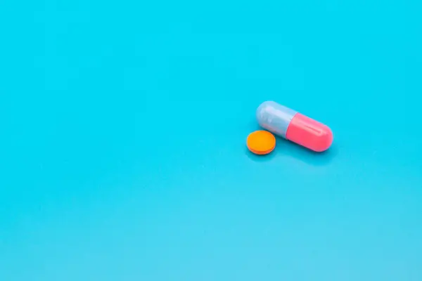 Tıbbi ilaçlar ve kapsüller masada. Mavi zemin üzerinde haplar ve metin için boşluk