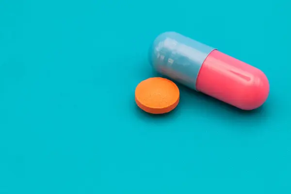 Tıbbi ilaçlar ve kapsüller masada. Mavi zemin üzerinde haplar ve metin için boşluk