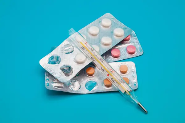 Tıbbi ilaçlar ve kapsüller masada. Mavi zemin üzerinde haplar ve metin için boşluk