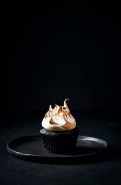 Tek çikolatalı kek ve kremalı pasta. Koyu arkaplan, siyah taş masa ve siyah seramik tabak. Dondurmanın modern şekli. Huysuz hala hayat. Kopyalamak için boşluk.