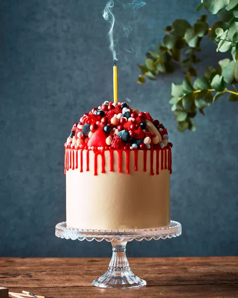 Mini çikolatalı kek, üzerine pembe jöle dökülüyor kaşıktan. Sahnenin arkasında bir şahıs var. Koyu gri arka plan ve siyah taş masa. Bir insan elementi ile yaşam tarzı dikey görüntü.