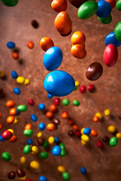 Görüntü, yukarıdan bakıldığında koyu kahverengi arkaplan üzerine düşen çeşitli renklerde şekerlemelerle dolu. Karanlık ışık. Stüdyo çekimi.