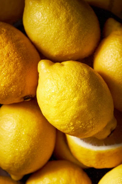 Görüntüyü dolduran limonların en üstteki görüntüsü. Yüksek kontrastlı canlı sarı renk. Turunçgilin güzel dokusu. Dikey resim.