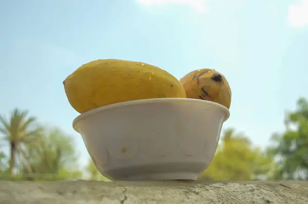 Hasır sepeti ve lezzetli mangolarla dolu bir adam. Sarı Mango 'nun yakın çekimi. Olgunlaşmış sarı mangolarla dolu bir sepet. Taze olgun mangolar sepetin içinde. Asya mangosu.