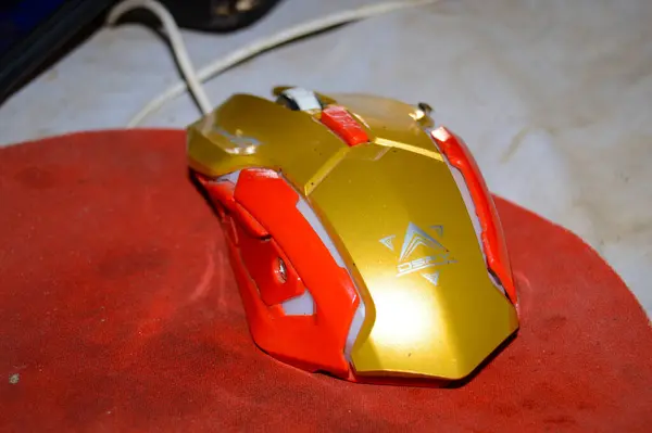 Beyaz arka planda bilgisayar faresi olan kırmızı bir robot oyuncak.