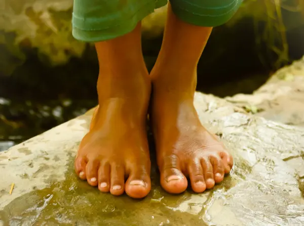 Küçük çocuk bir nehirde oturuyor..