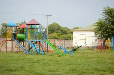 Şehir parkında gündüz vakti çocuk okulu ya da bahçe parkı için yapılmış rengarenk plastik oyuncaklarla oyna. Halk parkında çocuk parkı. Parkta egzersiz için ekipman.