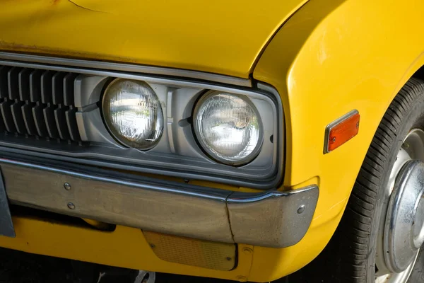 Front of classic retro car yellow,car tires and circle headlight car, headlight of a car,front light details yellow car,charm of classic retro cars.
