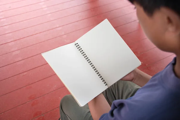 Closeup man holding blank notebook,man opening blank notebook on red wood floor background,writing idea and taking note,concept of lifestyle and education ,copy space,sustainability.