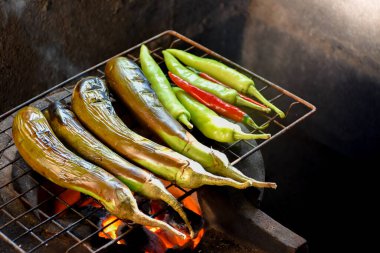 Patlıcan ve tatlı biber yeşili ve ızgarada kırmızı ve kapalı mutfakta kömür ızgarası yumuşak güneş ışığı Tayland yemeği ve BBQ 'nun arka plan bulanıklığı.