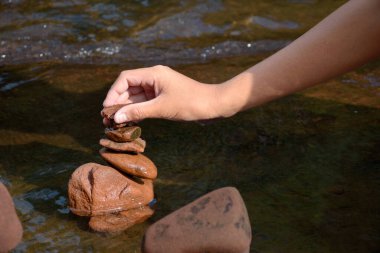 Taşı dengelemek için el ele tutuşan taş ve nehir zemininde kaya yığını..