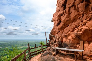 Bench on the edge of a beautiful orange rock cliff at the top of a mountain with a view of nature and the morning sky. Beautiful landscape of sky rock mountain are amazing scenery of Thailand. clipart