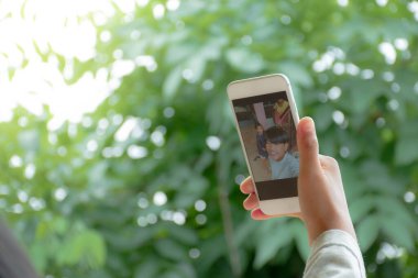 Yakın ekran cep telefonu görüntüsü, ellerinde akıllı telefonlar olan çocukların cihaz ekranına bakıp ormanın bulanık arka planında eğlenirken selfie çekmelerini sağlıyor..