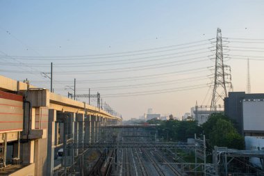 Bangkok, Tayland - 13 Ekim 2023: Bangkok şehir merkezi ve toplu taşımacılık, akşam günbatımında yüksek hızlı tren ve banliyö trenleri ve yüksek voltajlı elektrik direkleridir..