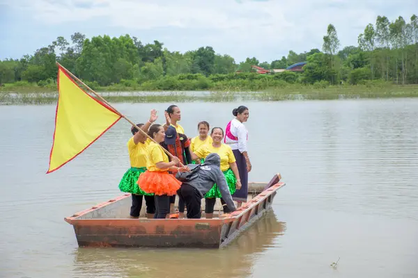Nakhon Phanom, Tayland - 12 Eylül 2023: Teknelerdeki Asyalı kadınlar göl ve ormanın arka planında geleneksel Tayland tekne yarışı festivalinde tezahürat ve teşvik yapıyorlar.