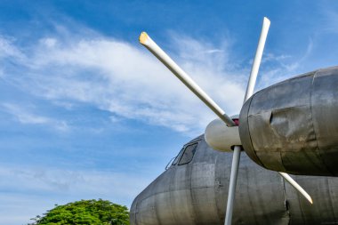 Eski ve paslı uçak parçaları ve park yerine park etmiş motor pervaneleri ormanın ve mavi gökyüzünün arka planına bakıyor..