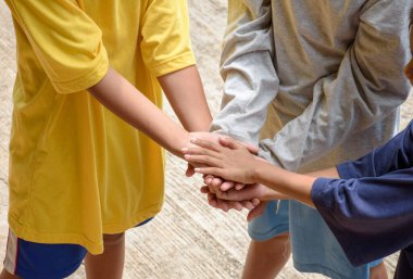 Takım çalışması çocuklar el ele tutuşur. Çeşitli çocuklardan oluşan bir grup, işbirliği ve beraberlik konsepti için bir araya gelerek topluluğa katılıyor..