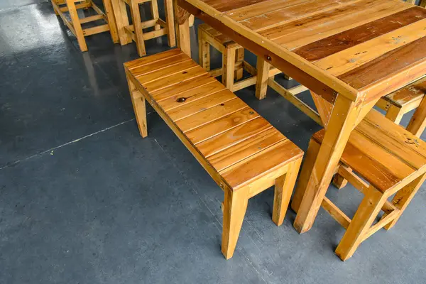 Güzel desenli ahşap masa ve mutfaktaki gri beton arka planda restoran tasarımı ya da yemek dekorasyonu için sandalyeler..