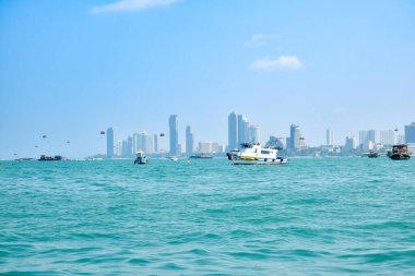 PATTAYA, THAILAND - 7 Mart 2024: Güzel mimari gökdelenler ve açık gökyüzü altında güzel mavi denizde birçok tekne ile deniz manzarası ve su aktiviteleri.