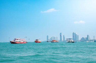 Güzel mavi deniz ve mimari binaların manzarası. Açık bir gökyüzünün altında denizde birçok gemi var. Pattaya deniz ve su aktivitelerinin manzarası.