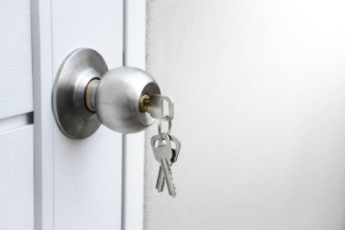 Kapıyı kilitlemeyi ya da anahtarı unutmayı unutmak için gümüş kapı tokmağını ve anahtarları beyaz ahşap kapıya kapat..
