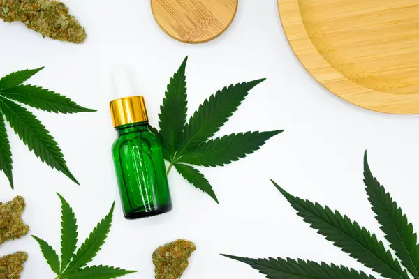 Kenevir özlü yeşil damlacık şişesi, beyaz arka planda esrar tomurcukları olan yağ ve kenevir yaprakları çıkarır. CBD yağı ve THC yağı kavramı için kenevir yağı ve kopyalama alanı.