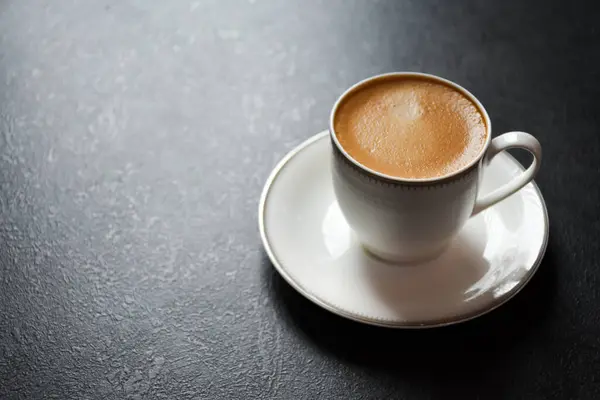 Siyah arka plan 2024 'te beyaz cam bir fincanda espresso ya da Americano kahvesi. Siyah masanın üzerinde güzel beyaz bir fincan kahve..