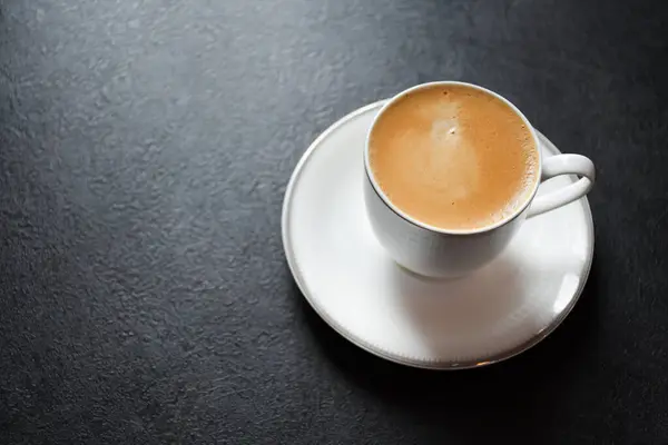 stock image Hot espresso coffee or Americano in a white glass cup on a black background 2024. Beautiful white cup of black coffee on the black table.