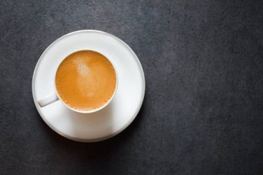 Top view of a morning espresso coffee or black coffee in a white glass cup on a black table background and copy space 2024. Beautiful coffee cup with foam of Americano on black background. clipart