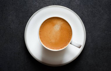 Sabah espresso kahvenin en üst görüntüsü ya da siyah masa 2024 'te beyaz cam bir fincanda sade kahve. Siyah arka planda köpüklü güzel kahve fincanı..