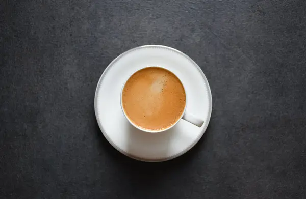 stock image Top view of morning espresso coffee or black coffee in a white glass cup on a black table background and copy space 2024. Beautiful coffee cup with foam of Americano on black background.