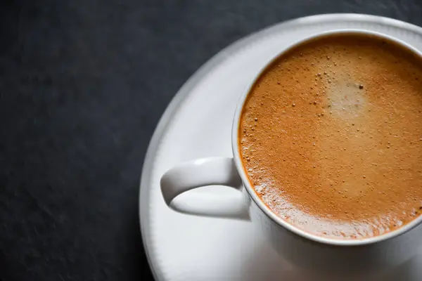 Sıcak espresso kahvesi ya da siyah arka plan 2024 'te beyaz cam bir fincanda Americano. Siyah masanın üzerinde güzel beyaz bir fincan kahve..