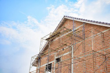 Modern evler ve konut konsepti 2025 olan kahverengi inşaat alanı. Mavi gökyüzü arkaplanına karşı inşaat ve inşaat çalışmaları devam ediyor.