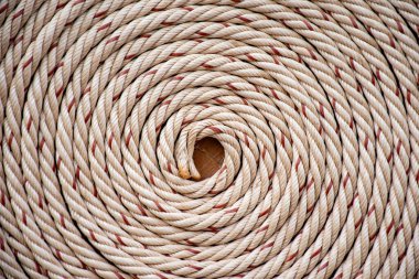 Kırmızı çizgileri olan beyaz ip ve ahşap masa zemininin üst kısmından sıcak bir tonda yuvarlanmış. 2025 rulo arkaplan dokusunda örülmüş ip. Eski bir ipin fotoğrafı..