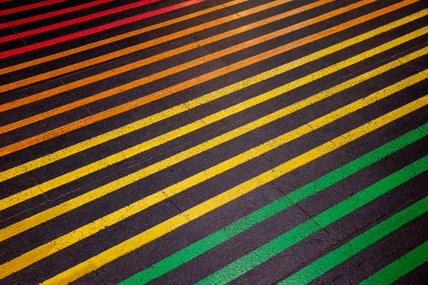 stock image Colorful lines on the black floor and walkway. Crossing the street on a multi colored crosswalk painted with the colors of the pride flag. Rainbow color.