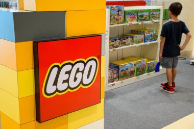 PATTAYA, THAILAND - APRIL 28, 2024: Boy standing and looking at lego toys in Lego store in a shopping mall. Close up of LEGO logo sign and plastic construction toys shelves on disp lay at the stores. clipart