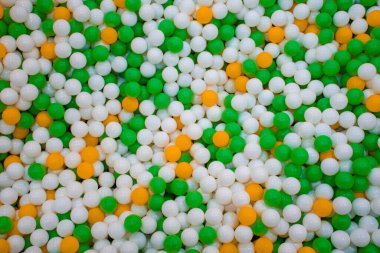 Arka planda güzel renkli plastik topların üst görüntüsü, çok renkli yeşil, turuncu ve beyaz topların dokusu. Renkli toplarla yüzme havuzu.