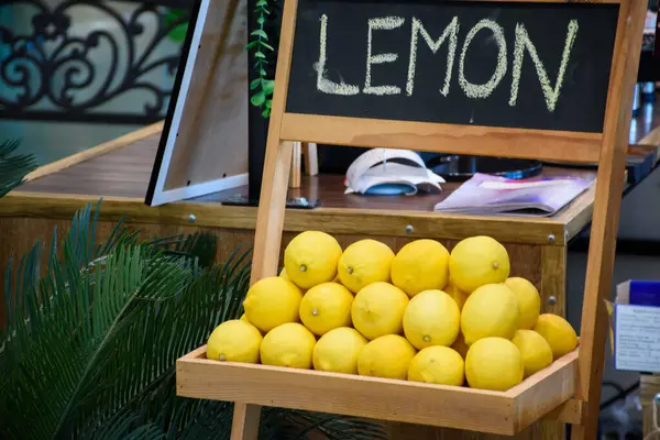 Tahta bir kutuda bir grup limon ve üzerinde Lemon 'un yazılı olduğu karatahta levhası. Dükkanın arka planında tahta bir kutuda limonlar.