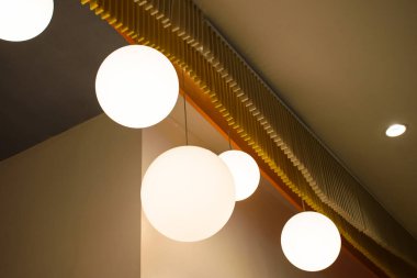 Modern ev tarzında kahverengi duvarlı bir grup lamba, modern güzel tavan ışığı manzaralı. Minimalist iç mekan 2024 'ün sıcak tonlarında dairesel ampullerle süslenmiştir..