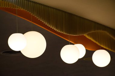 Lambaların içinde modern ev tarzında kahverengi bir duvar, modern güzel tavan ışığı manzarası. Minimalist iç mekan 2024 'ün sıcak tonlarında dairesel ampullerle süslenmiştir..