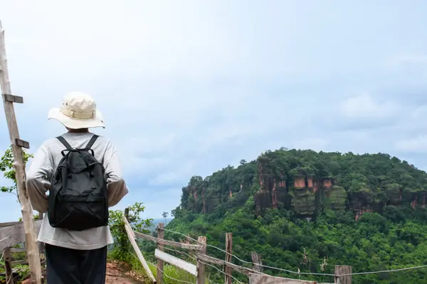 Yürüyüşçü bir dağın tepesinde duruyor ve güzel kayalık dağların ve güzel doğal ormanın tadını çıkarıyor. Mavi gökyüzünün arka planında, Tayland 'da turistik bir eğlence..